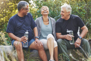 A group of senior citizens sitting outdoors in the sun laughing, discussing paying a mortgage in retirement